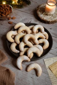 Die besten Vanillekipferl mit Mandeln und Puderzucker auf einem Teller