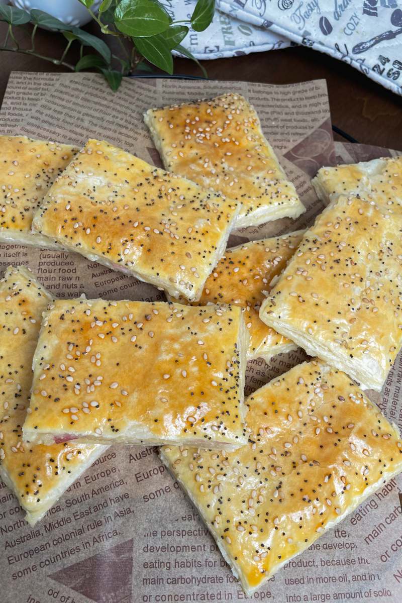 Blätterteigtaschen mit Schinken und Käse auf einem Backpapier