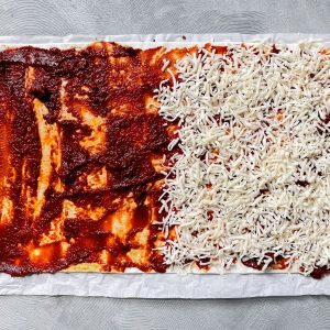 Tomatenmark und Käse auf dem Blätterteig verteilt