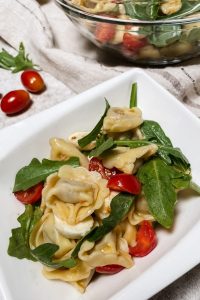 Tortellini Salat serviert in einer weißen Schale