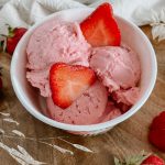 Erdbeereis im Eisbecher mit zwei frischen Erdbeerscheiben