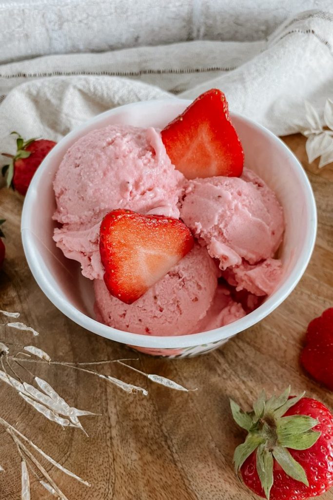 Erdbeereis im Eisbecher mit zwei frischen Erdbeerscheiben