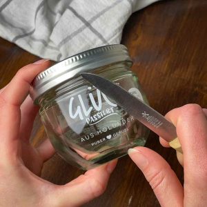 Die Schrift vom Glücksglas wird mit einem Messer entfernt