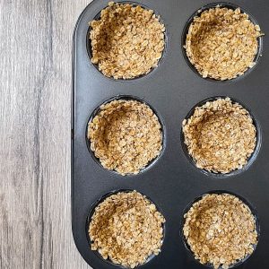 Haferflockenmasse für die Granola Cups in die Muffinform angedrückt