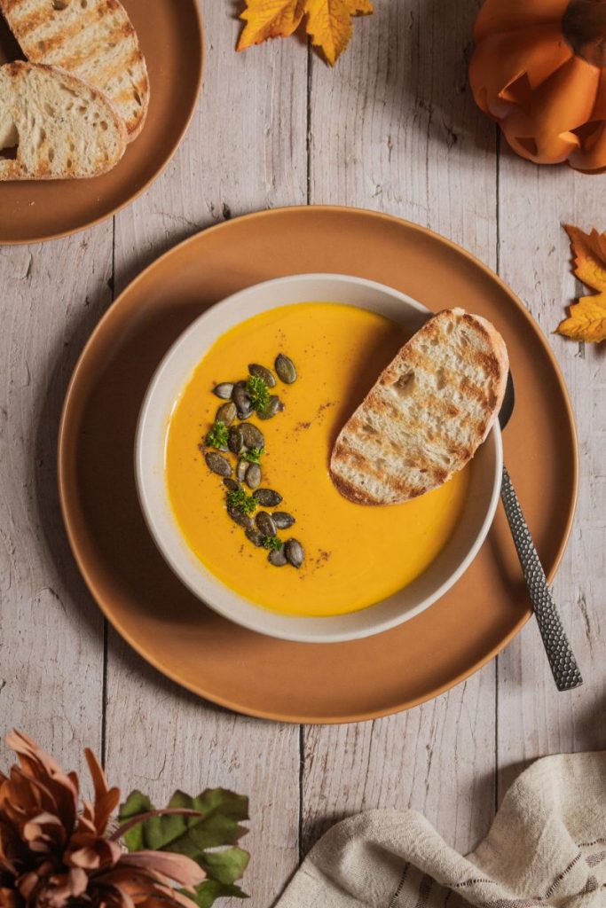 Hokkaido Kürbissuppe mit Kürbiskerne und einem Stück Brot