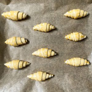 Mit Eigelb bestrichene Mini Croissants auf dem Backblech