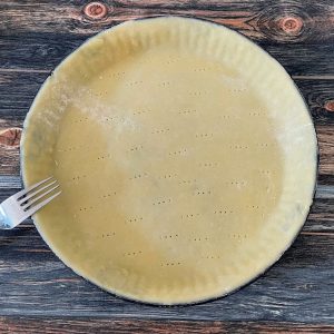 Mürbeteig in einer Backform ausgrollt und mehrfach eingestochen