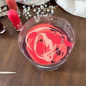 Halbierte Plastikflasche mit Wasser und einem Mix aus Nagellackfarben