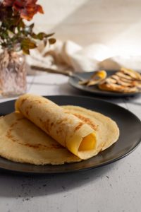 Pfannkuchen zusammengerollt auf einem Teller