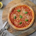 Pizza Margherita mit Basilikum auf einem Holzbrett