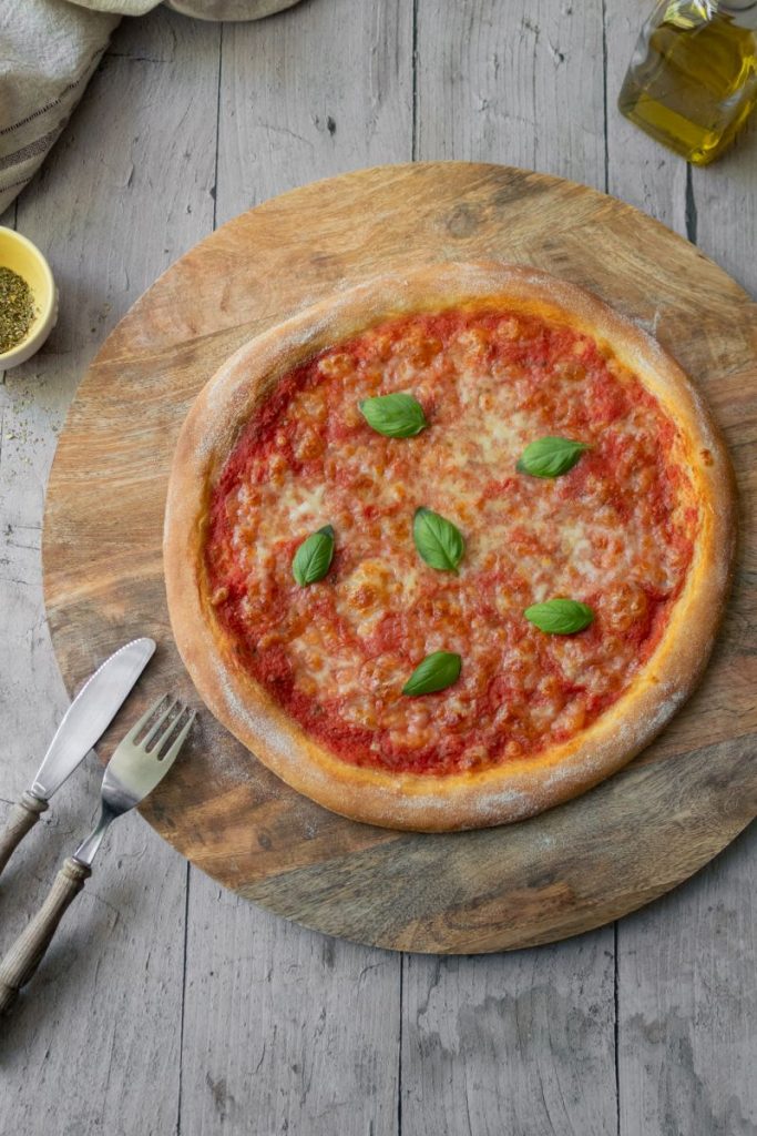 Pizza Margherita mit Basilikum auf einem Holzbrett