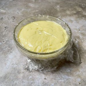Puddingcreme für die Erdbeertörtchen mit Frischhaltefolie bedeckt
