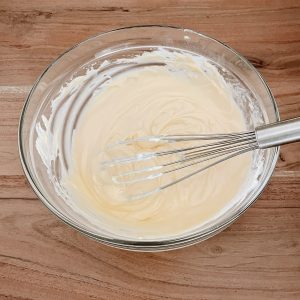 Angerührter Vanillepudding in einer Glas-Schale mit einem Schneebesen