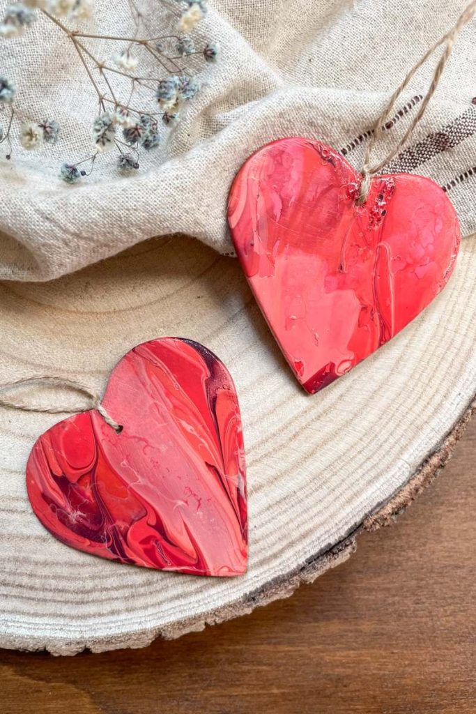 Zwei fertige Herzen aus Modelliermasse auf einem Stück Holz